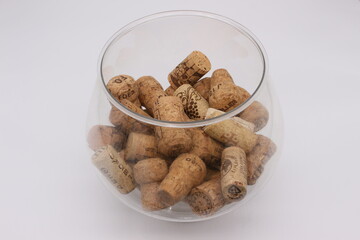 Image of a large glass with wine corks on a light background.