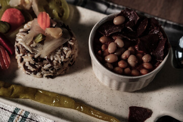 traditional turkish white beans stew with bacon, boiled rice and salted marinade vegetables, cucumbers, green tomatoes, carrot, pepper, served ready to eat kuru fasulye