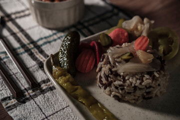 traditional turkish white beans stew with bacon, boiled rice and salted marinade vegetables, cucumbers, green tomatoes, carrot, pepper, served ready to eat kuru fasulye