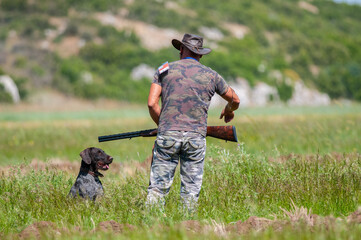 The hunter stalks his prey with his gun and dog.