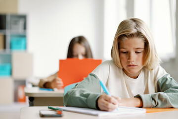 Pupil writitng notes stationery serious learning class