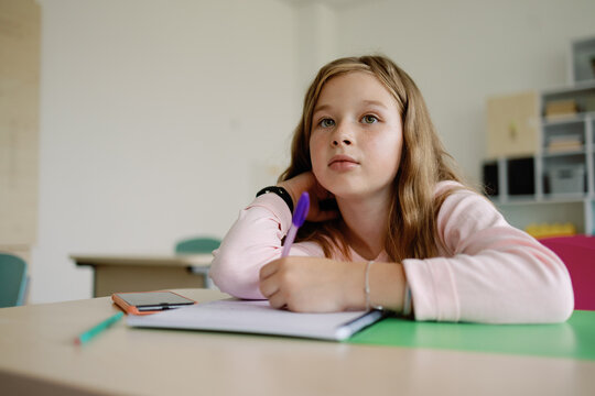 Daydreaming schoolgirl at desktop