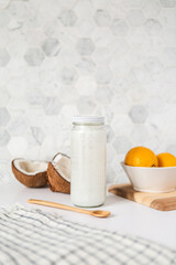 Fototapeta na wymiar Coconut oil jar on kitchen counter with fresh ingredients 