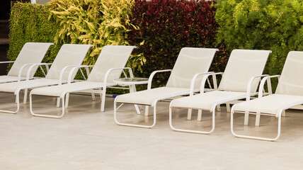 White beach chairs next to a swimming pool in a leisure area in a Brazilian residential condominium
