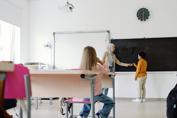 Schoolteacher supervising pupil at class 