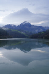 Txindoki with snow. Mount Txindoki reflected in the Ibiur reservoir, Basque Country.