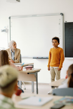 Schoolboy telling something in front of school class