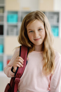 Smiling girl with backpack in school hallway