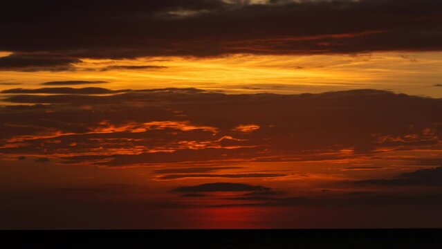 Timelapse Sunset on the Atlantic Ocean. The sunlight cresting the cloudy horizon...painted in reds, oranges and yellow