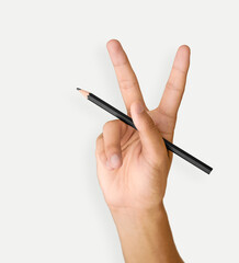 Hand showing peace gesture, writes on white. A man's hand holds a black pencil on white background,...