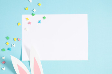 Easter party concept. Flat lay, top view of blank sheet of paper, Easter decorations, funny bunny...