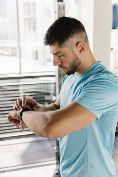Portrait of a man in gym looking at his smartwatch