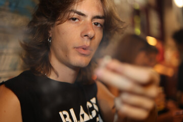Long hair rock style man smoking and offering cigarette to the camera