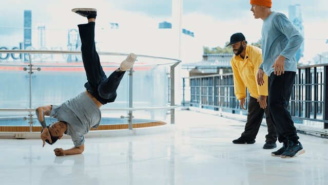 Hipster perform break dance while friend encourage him at mall. Diverse or multicultural street dancer clapping hands while watching young dance practice street dance. Outdoor sport 2024. Endeavor.