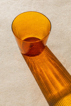 Empty orange cocktail glass on a beige background