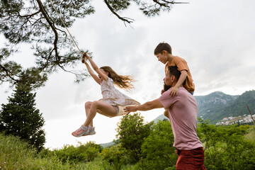 Father and kids play with tree swing