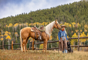 Blonde Cowgirl on a Palomino Horse in the Colorado Rocky Mountains in the Fall with Aspens in the...