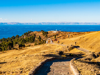 Amazing view of Amantani island at sunset, with cultivated fields and stone path that goes down to the coast, lake Titicaca, Peru 
