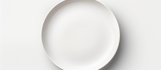 A white ceramic plate is placed on a white table, creating a simple and clean aesthetic. The plate is empty and displayed from a top-down perspective.