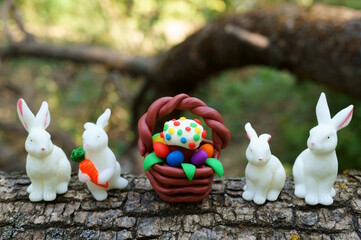 Easter basket made of plasticine and toy hares. - obrazy, fototapety, plakaty