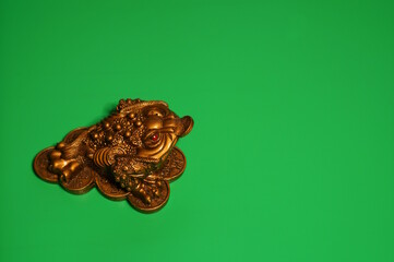 A statuette of a metal toad on a green background.