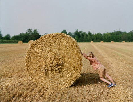 A kid and moving a big stack of hay
