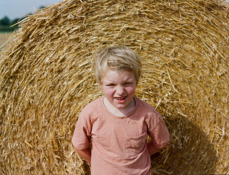 A laughing kid and a stack of hay
