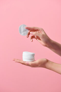 Front view of hand model holding cotton pad in pink background