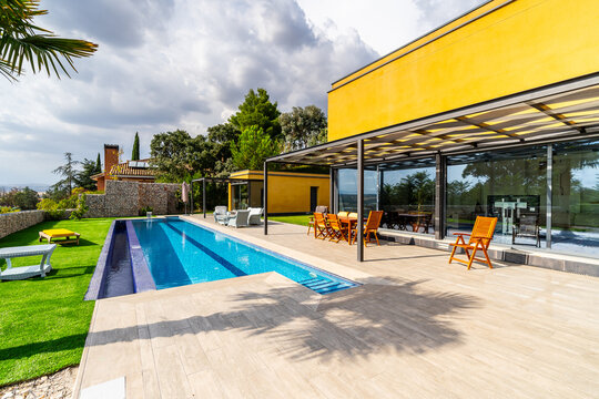 modern villa on a sunny day, with its garden, swimming pool and porch