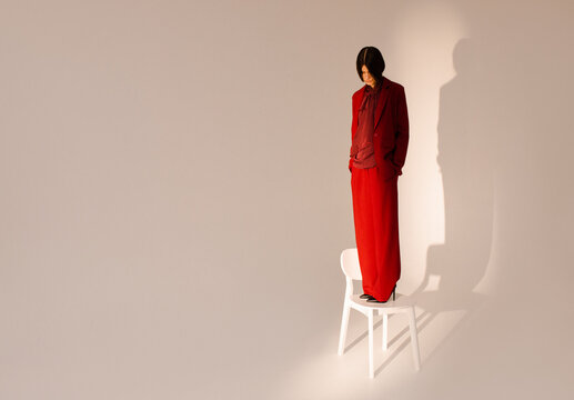 Thoughtful and apathy woman is standing on a chair in studio 
