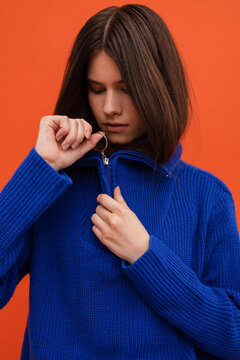 Brooding woman pulling up the zipper of the sweater