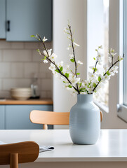 Vase with fresh spring flowers on dinning table,  modern kitchen in Scandinavian interior style in background