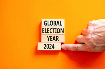 Global election year 2024 symbol. Concept words Global election year 2024 on beautiful block. Beautiful orange table background. Voter hand. Business Global election year 2024 concept. Copy space