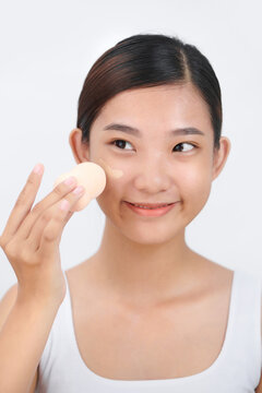 Smiling woman using make-up sponge on face