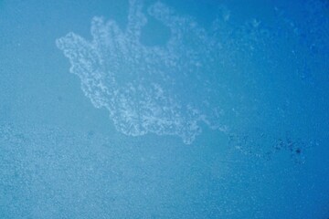 Abstraktes Motiv mit Eismuster vor blauem Himmel mit Licht bei Sonne, Eis und Frost am Morgen im Winter