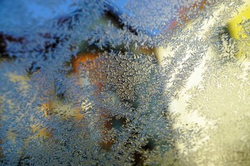 Abstraktes Motiv mit Eismuster vor Häusern und hellblauem Himmel bei Frost, Sonne und Eis am Morgen im Winter