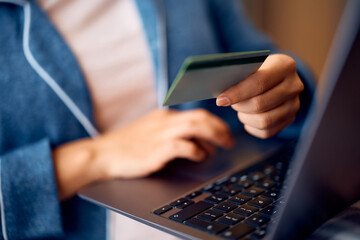 Close up of woman buying online with laptop and credit card at home.