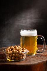 Glass of cold beer and peanuts on the table.