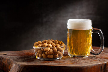 Glass of cold beer and peanuts on the table.