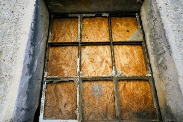 Altes rostiges Gitterfenster vor brauner Holzspanplatte 