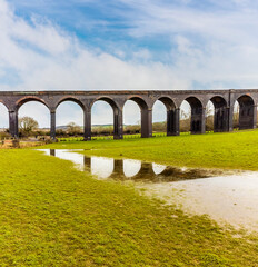An aerial view of reflections in rain soaked fields beside the spectacular Harringworth Viaduct on a bright winter day