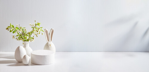 Empty round white podium for product presentation. Spring flowers in a vase and easter eggs on a light background - obrazy, fototapety, plakaty
