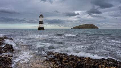 A low point of view and a long exposure to show movement in the waves.The view is off Pen Mon point at Trwyn Du lighthouse and in the distance is puffin island - 753870012