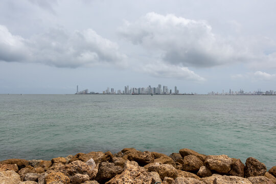 comulus of stones on the seashore with a view of white buildings in the background