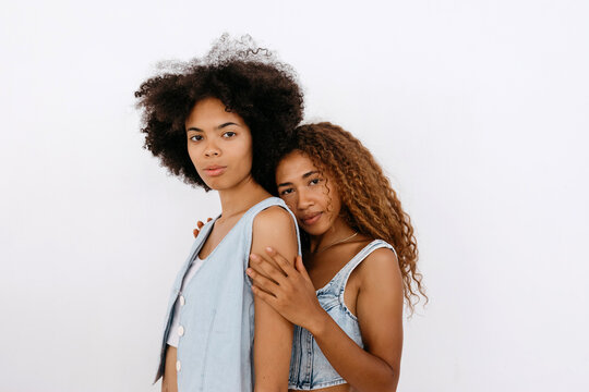 Diverse women hugging in studio and looking at camera