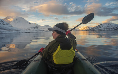 Woman with a paddle paddling packraft on a calm body of water