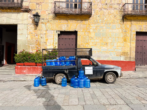 A pickup truck parked on the street full of blue water containers 