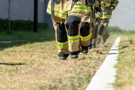 Firefighters Running Around A Green Area Outside The Fire Station