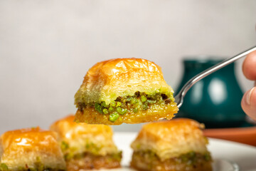 Pistachio baklava. Turkish and Arabic cuisine delicacies. He is holding a slice of baklava with a fork. Close up