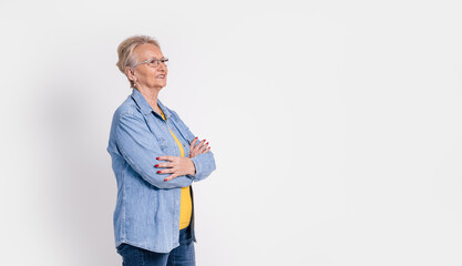 Portrait of pensive old businesswoman with arms crossed looking away confidently on white background